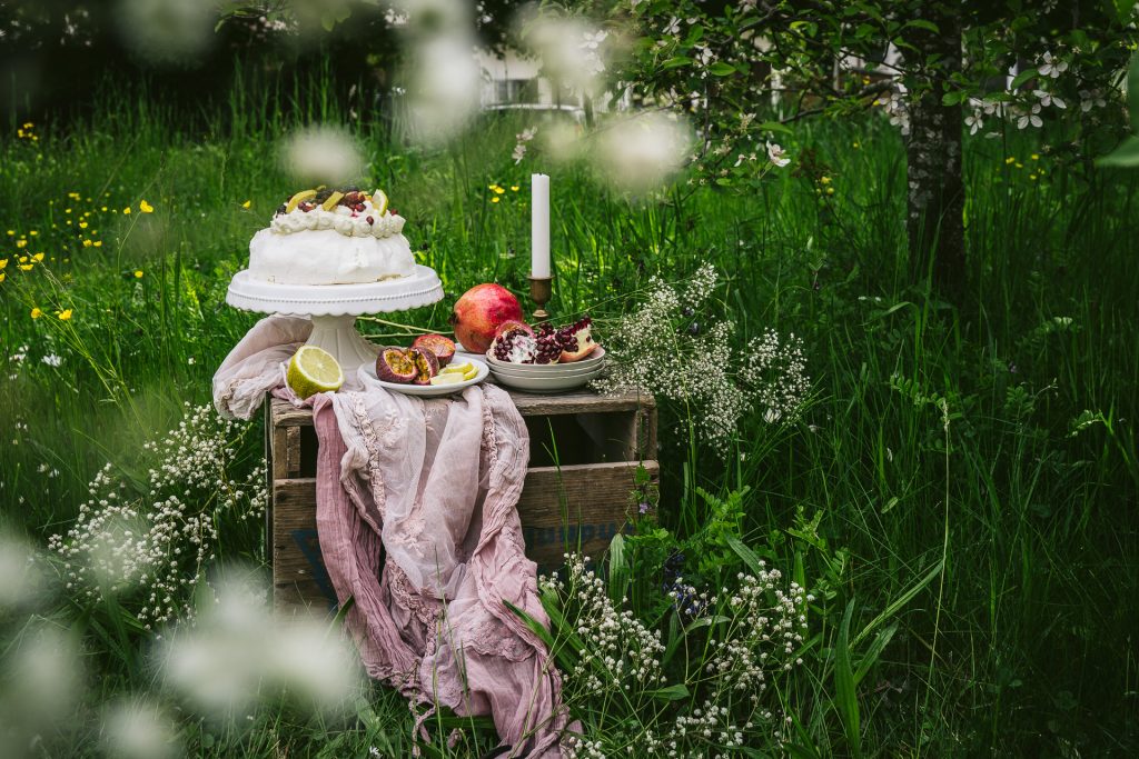 sommerliche Pavlova mit Früchten im Garten Food Fotografie granatapfel Apfelblüte blumen